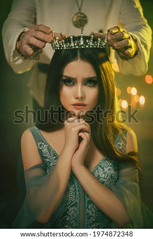 Fantasy medieval couple. Image of lovers - king and queen. hands of man put gothic crown on girl's head. Coronation of woman. vintage costume clothing. Portrait close up girl princess beauty face