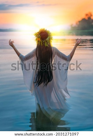 ivan kupala. silhouette happy fantasy vintage woman standing in water hands raised to sky. Slavic girl herbal wreath, long hair white wet dress pagan ritual praying to sun. river sunset Back rear view
