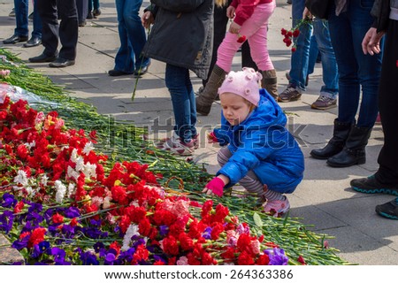 2014. Russia, St. Petersburg - MAY 9: day of victory, memory of heroes. The memory of soldiers in Great Patriotic War.   little girl brought flowers to the graves of the soldiers of World War II