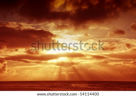Sunset over sea with moody sky, dark storm clouds, and red light. Makes a good background.