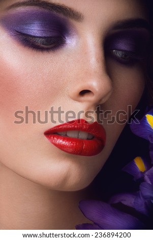Close-up portrait of beauty young woman with purple eyeshadows and red lips with iris flowers