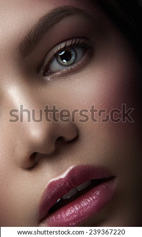 Close up portrait of belle young maiden with green eyes, natural make-up and rose lipstick, with head to the left looking at you and breathing through her open lips on dark background