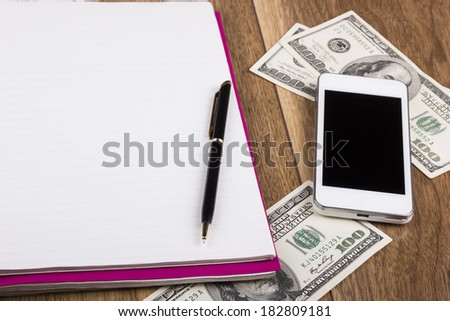 Money, phone, notepad and pen on wooden background