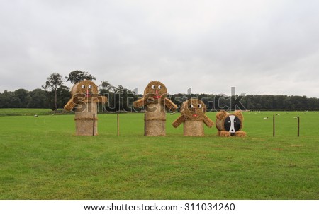 A Family of Scarecrows made from Straw Bales in a Field with Sheep in Knutsford, Cheshire, England, UK