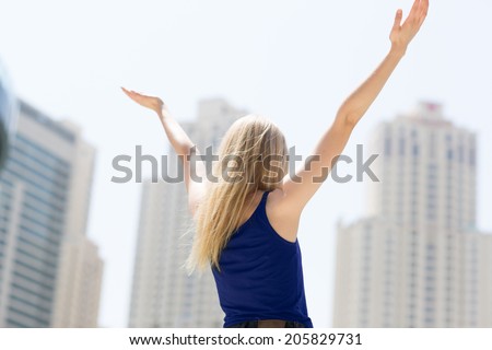 Unrecognizable woman overlooking the city with her arms up in the air. Celebration concept.