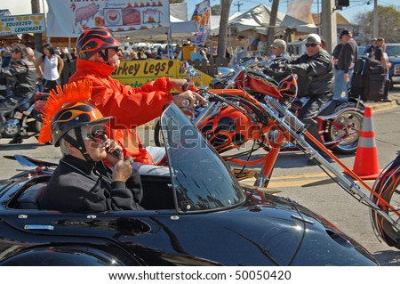 DAYTONA BEACH, FL - MARCH 6: Older biker couple cruising down Main Street while woman talks on cell phone during \