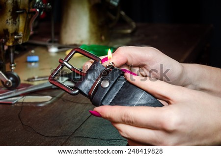 Close up of girl hands repairing a black leather belt