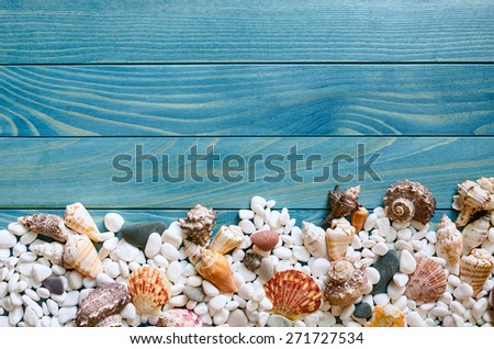 Summer sea background. Natural wooden border with sea shells and small rocks on a background of colourful turquoise blue painted wooden boards with space for text.