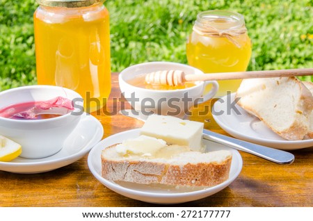 Summer outdoor breakfast with clear locust honey, bread with butter and milk, close-up, horizontal
