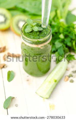 Healthy green smoothie with spinach, kiwi and orange in a retro jar on light wooden table. Top View
