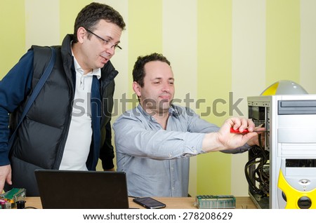 Happy computer engineer repairing broken computer while  male customer is looking scared. Isolated on retro striped green and yellow wallpaper.