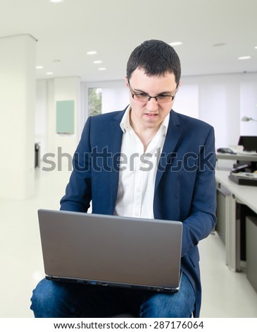 Young businessman wearing glasses and paying games in his office