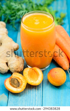 Glass of apricot and carrot juice on colourful turquoise blue painted wooden boards