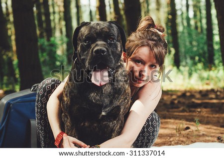 Young hipster girl on picnic in hug with her big dog. Vintage Instagram style effect, soft and selective focus, grain texture visible on maximum size