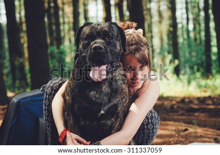 Young hipster girl on picnic in hug with her big dog. Vintage Instagram style effect, soft and selective focus, grain texture visible on maximum size