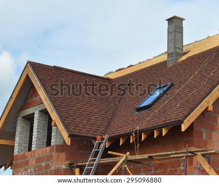 Roofing and building new house with modular chimney, bitumen tile, skylights and eaves. Roofing construction.