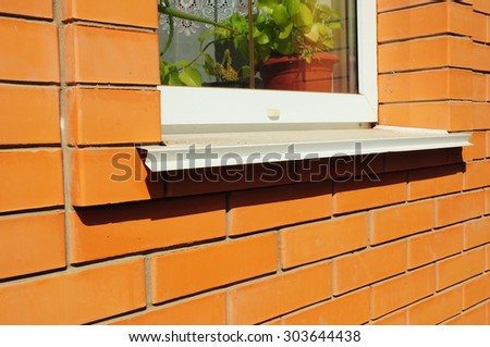 Close-up on single plastic window and metal sill detail. Install window against brick wall facade.