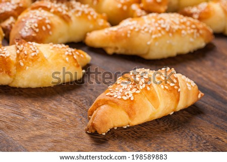 Mini croissants filled with cheese, with sesame on a wooden table