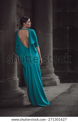 Fashion portrait of a young woman in a dress. Shot in a greek-style stone temple.