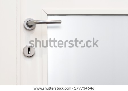Aluminium door knob on the white door with a glass.