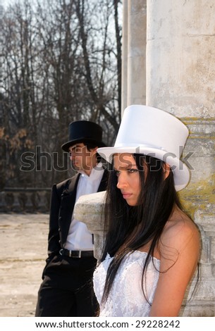 Girl in the white top hat and man in the black top hat in a neglected estate