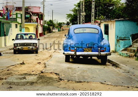VARADERO, CUBA - DECEMBER 3, 2013: Classic American cars, colonial building in streets of Varadero and road full of holes, where old cars are relic of Cuban revolution and still attracts tourists.