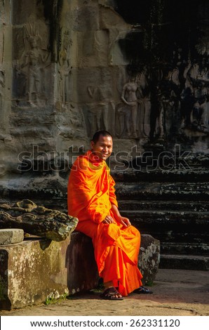 CAMBODIA, SIEM REAP ANGKOR WAT - NOVEMBER 6, 2014: Buddhist monk in reddish yellow robes in one of the famous temples of Angkor Wat, Siem Reap, Cambodia
