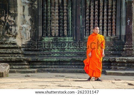 CAMBODIA, SIEM REAP ANGKOR WAT - NOVEMBER 6, 2014: Buddhist monk in reddish yellow robes in one of the famous temples of Angkor Wat, Siem Reap, Cambodia