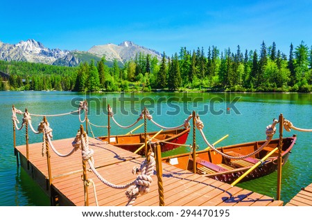 Red wooden boats moored to the pier on mountain lake Strbske Pleso in the High Tatra National Park, Slovakia, Europe