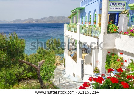 KALYMNOS, GREECE - MAY 01, 2015: Panoramic view on typical Greek restaurant with flowers and white teracce having clear view on sea landspace with islands, Greece