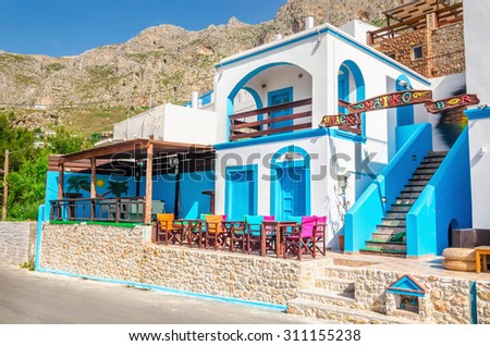 KALYMNOS, GREECE - MAY 01, 2015: Panoramic view on typical Greek modern blue and white restaurant with colorful chairs and tables, Greece