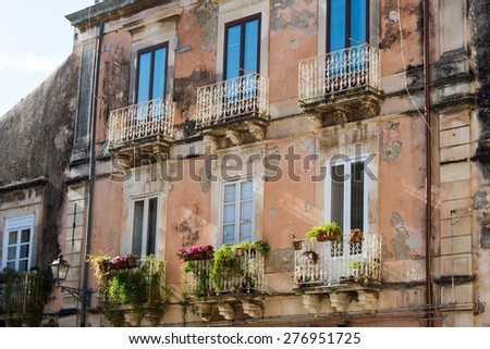 Building facades with windows and wrought iron balconies very spoiled in the historic center of Ortigia, Syracuse, Sicilia, Italy
