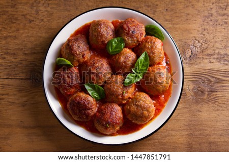 Meatballs in tomato sauce, garnished with basil in bowl on wooden table. View from above, top studio shot Foto stock © 