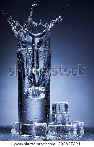 Water splash in a glass. Ice cubes and water drops outside of the glass.