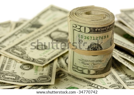 A roll of twenty dollar bills on a pile of one dollar bills