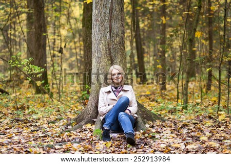 Pretty young woman sitting under tree in a forest