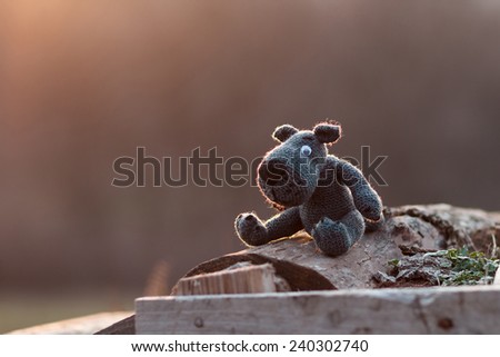 knitted toy wolf sits astride on a log