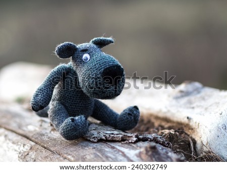 Toy wolf, knitted from wool, sitting on a log