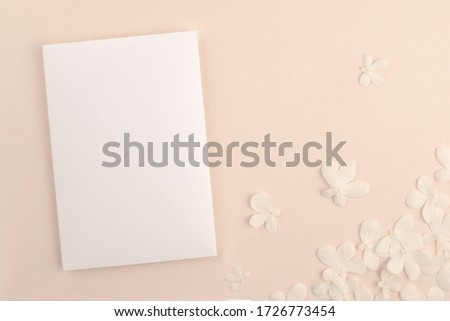  Romantic wedding blank invitation card mock up on soft pink background with small white flowers. Modern neutral minimal feminine stationery presentation design. 商業照片 © 