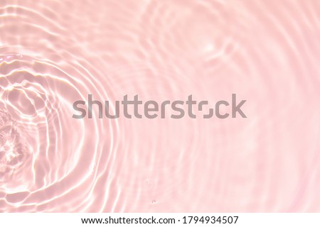Closeup of pink transparent clear calm water surface texture with splashes and bubbles. Trendy abstract summer nature background. Coral colored waves in sunlight.