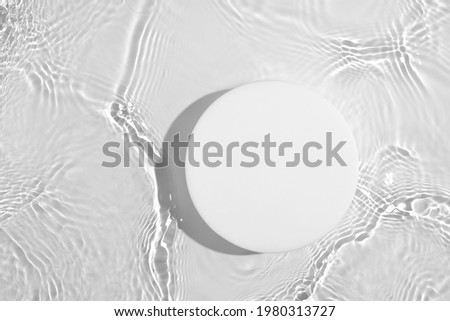 Empty white circle podium on transparent clear calm water texture with splashes and waves in sunlight. Abstract nature background for product presentation. Flat lay cosmetic mockup, copy space. 商業照片 © 