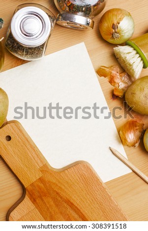 Paper, pencil, jug of olive oil, potatoes, onion, cutting board and spices