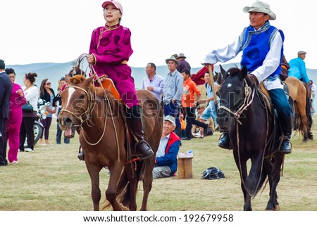 NADAAM HORSE RACE OUTSIDE ULAANBAATAR, MONGOLIA - JULY 12, 2010: Horseback woman and man in traditional costume at Nadaam horse race, the most important festival of the year in Mongolia.