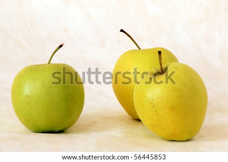 Three yellow apples on painted background