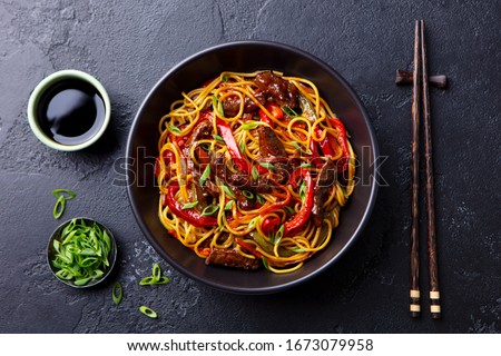 Stir fry noodles with vegetables and beef in black bowl. Slate background. Close up. Top view. Foto d'archivio © 