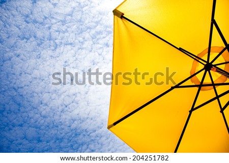 Yellow sun umbrella on a blue sky. Summer background.