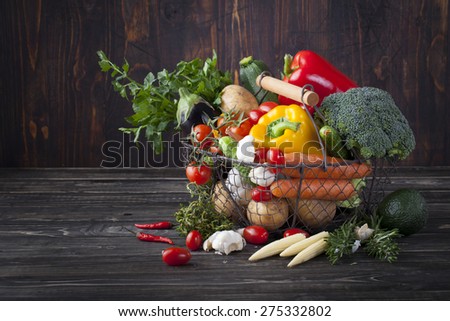 Vegetables variety in a wire basket on a wooden background. Copy space