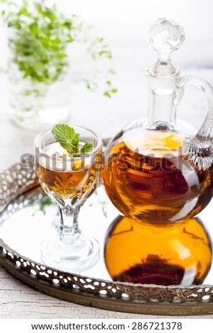 Herbal, mint homemade liquor on a white wooden background. Russian traditional strong spirits