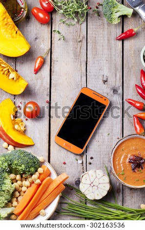 Fresh vegetables with mobile cell phone on a wooden background. Cope  text space.