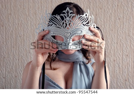 Pretty woman with a mask in his hand. Focus on the mask.
